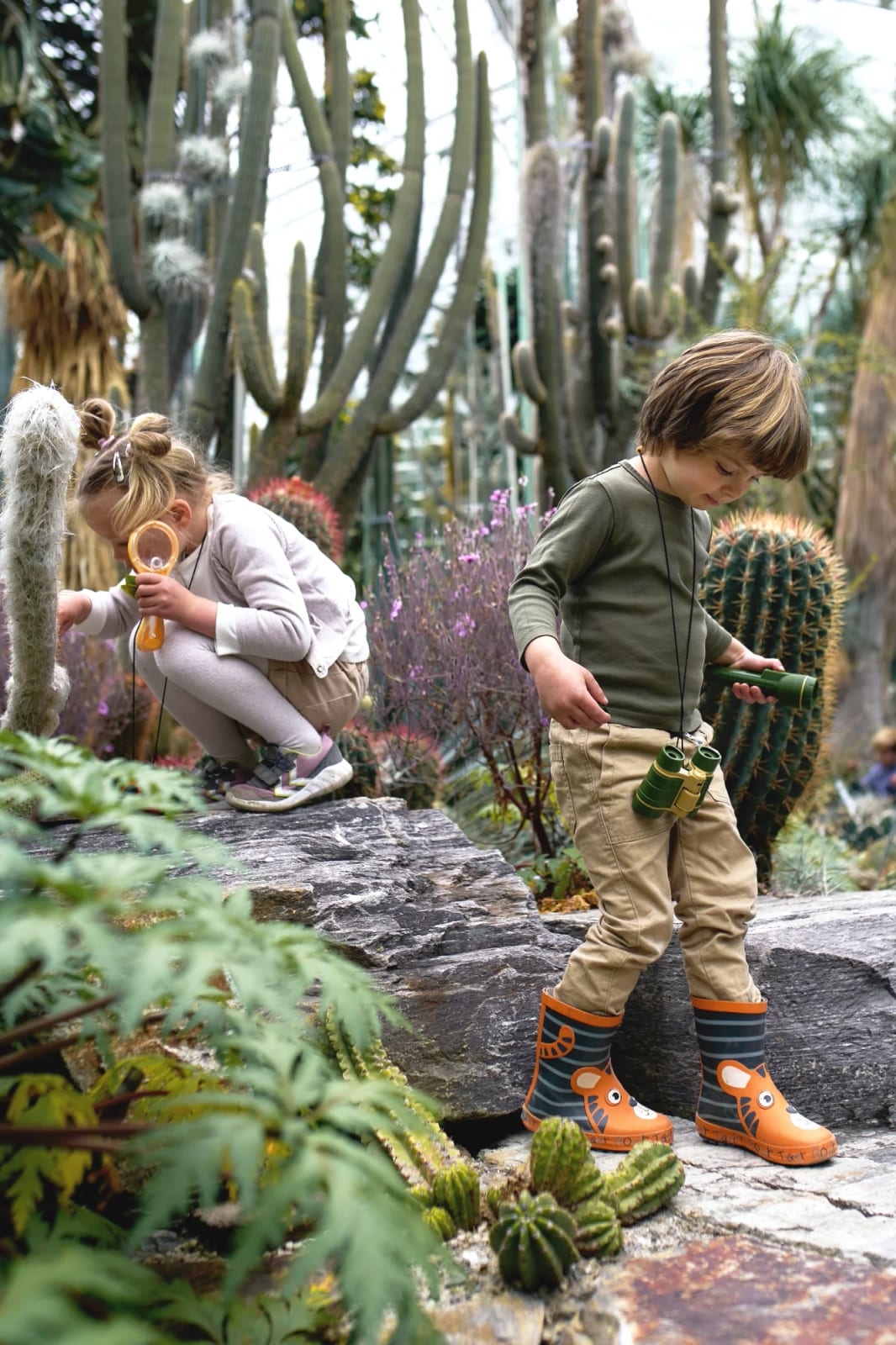 Little explorer with binoculars among towering cacti during a kids photoshoot in Munich
