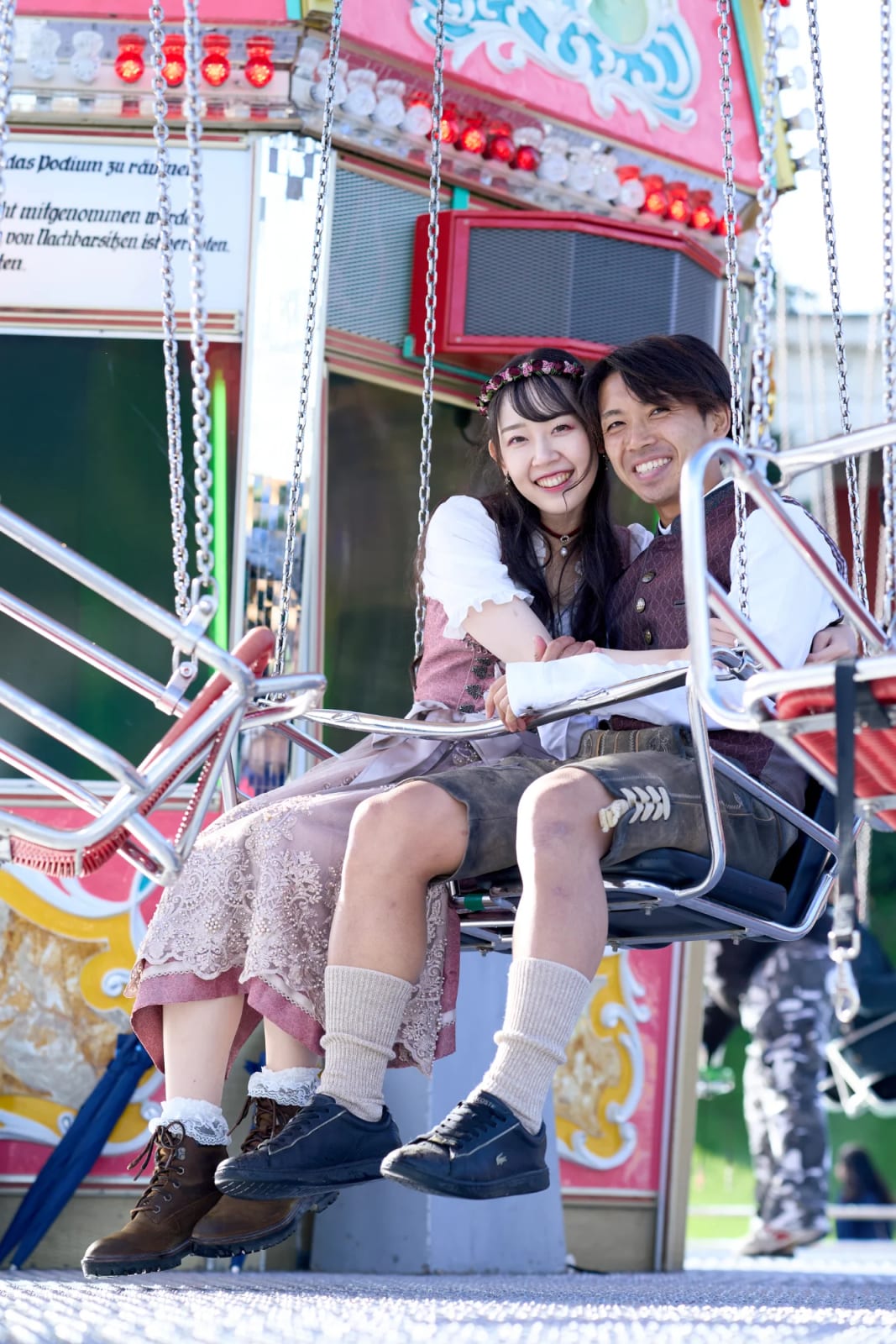 Engaged couple in traditional Tracht laughing during their engagement photoshoot at Oktoberfest in Munich